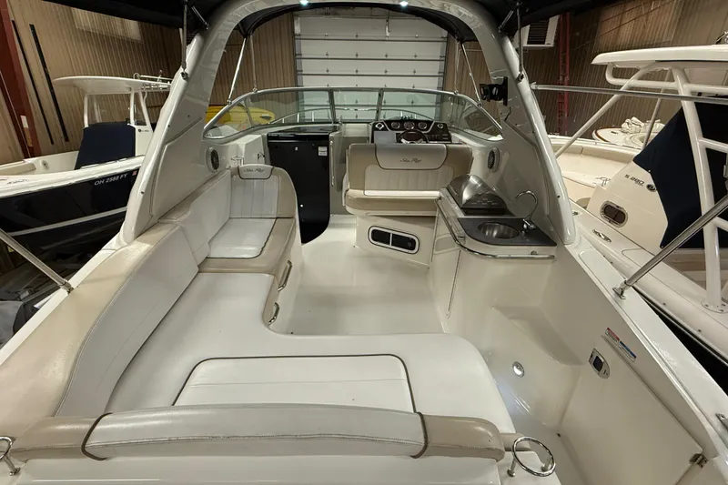Slide: The Image of 2012 Sea Ray Sundancer 280 interior with seating, helm, and kitchenette in a showroom. - 5