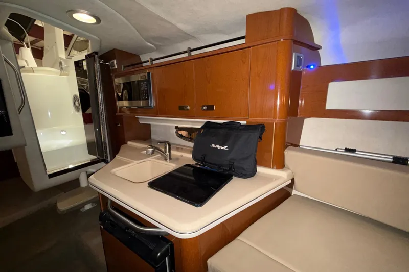 Slide: The Image of Interior of 2012 Sea Ray Sundancer 280, featuring kitchenette with sink, stove, and seating area. - 57