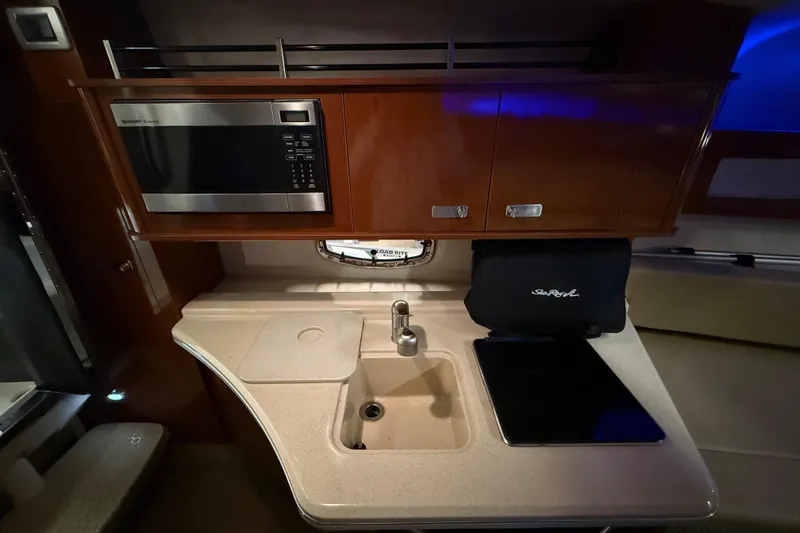 Slide: The Image of 2012 Sea Ray Sundancer 280 galley with microwave, sink, and storage cabinets. - 59
