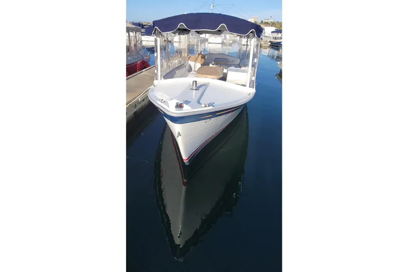 Slide: The Image of 2013 Duffy Electric Boats 21 docked, featuring a blue canopy and clear waters. - 2