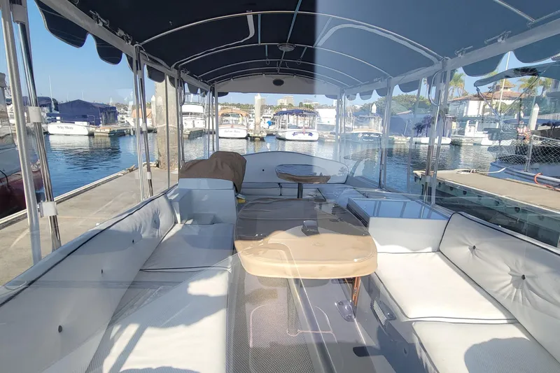 Slide: The Image of Interior view of a 2013 Duffy Electric Boats 21, featuring spacious seating and waterfront backdrop. - 3