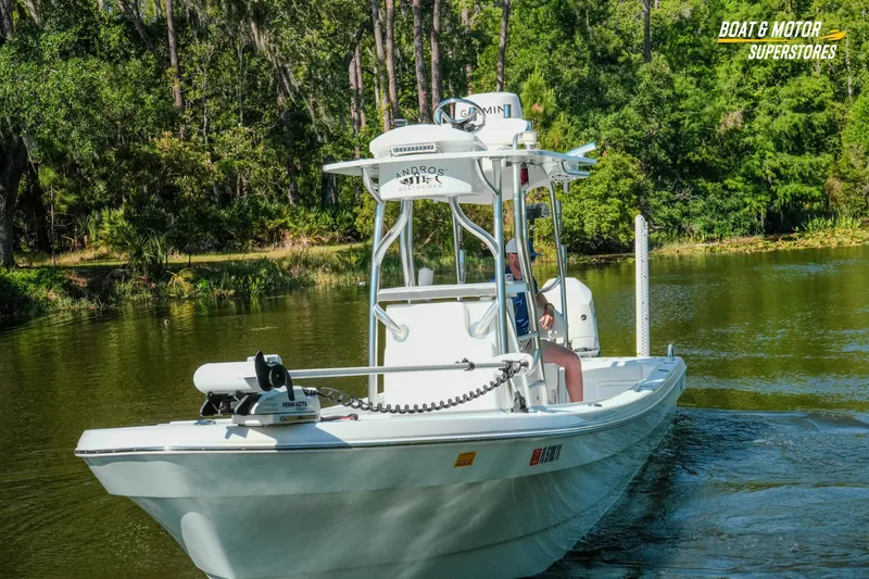 Slide: The Image of 2023 Andros 26 Tarpon boat cruising on a serene river with lush greenery. - 15