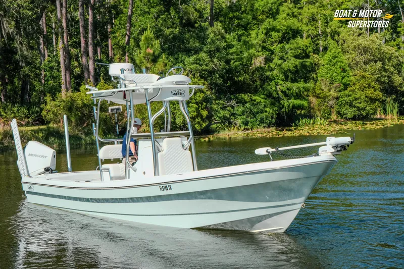 Slide: The Image of 2023 Andros 26 Tarpon boat cruising on a serene lake with lush greenery. - 18