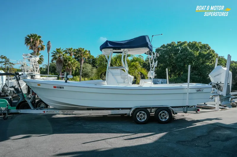 Slide: The Image of 2023 Andros 26 Tarpon boat on trailer, parked outdoors with palm trees in background. - 2