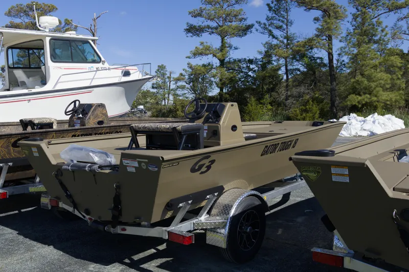 Slide: The Image of 2026 G3 Gator Tough 18 CC boat on trailer, parked outdoors with trees in background. - 9
