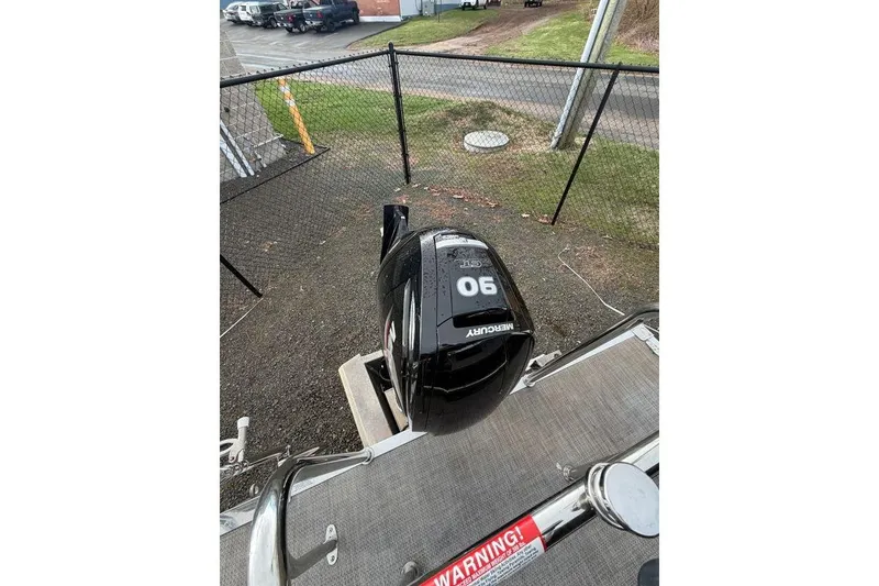 Slide: The Image of 2024 Massimo Marine P-22 Limited with Mercury 90 outboard motor, parked near a fence. - 11
