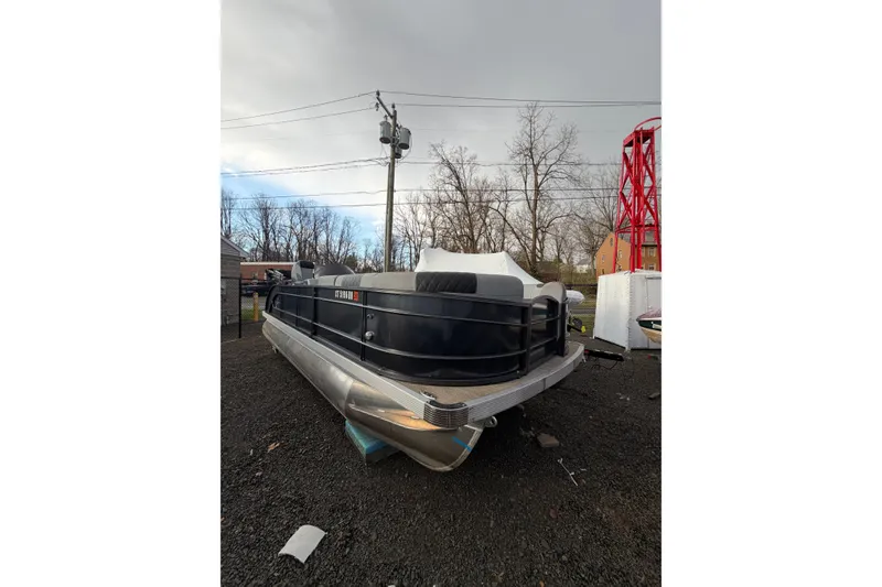 Slide: The Image of 2024 Massimo Marine P-22 Limited pontoon boat on gravel lot, overcast sky. - 2