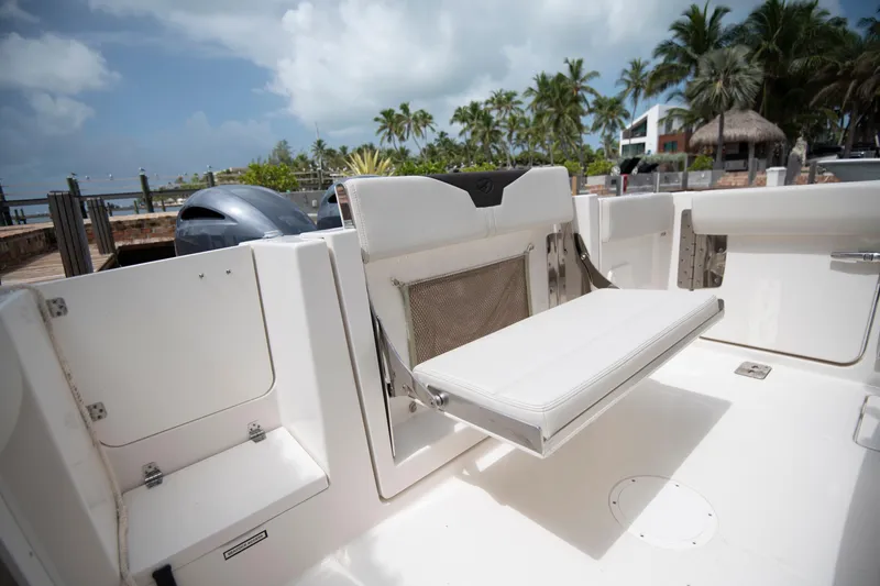 Slide: The Image of 2027 Sailfish 272 CC boat interior with foldable seating, docked near palm trees and waterfront. - 22