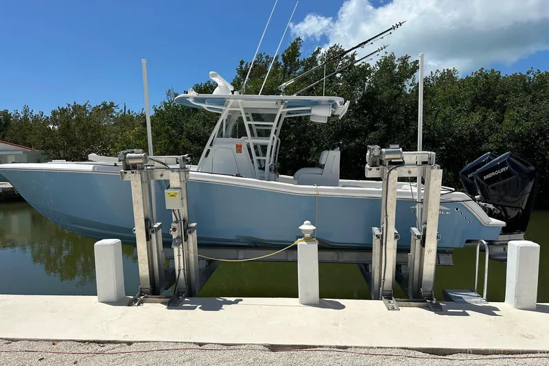 Slide: The Image of 2021 Invincible 33 Open Fisherman boat on lift, docked by lush greenery. - 4