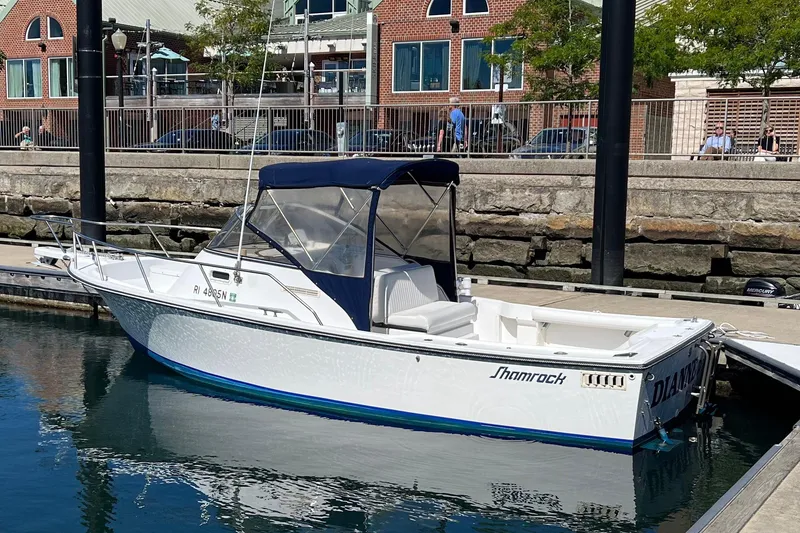 The Image of 1993 Shamrock 220 Walkaround boat docked at a marina, featuring a blue canopy. - 0