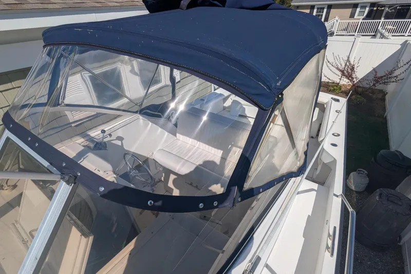 Slide: The Image of 1993 Shamrock 220 Walkaround boat with blue canopy and clear windshield in a residential setting. - 17