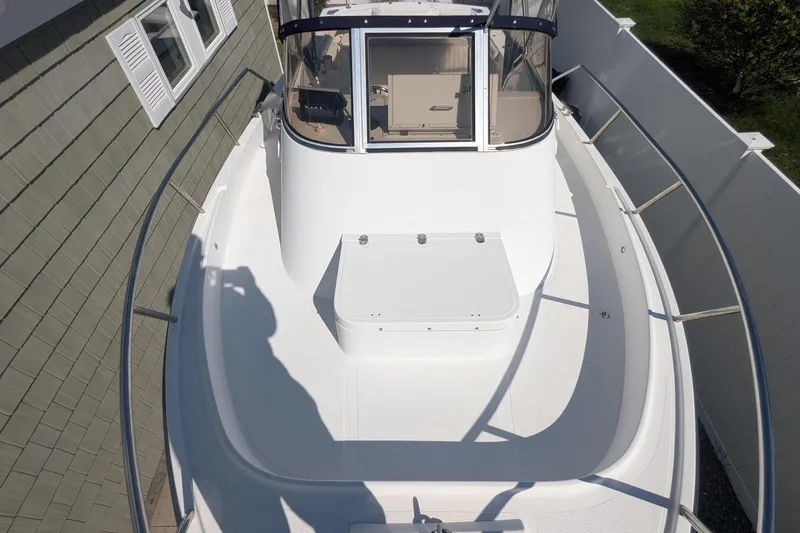 Slide: The Image of 1993 Shamrock 220 Walkaround boat with spacious deck and enclosed cabin, docked beside a house. - 18