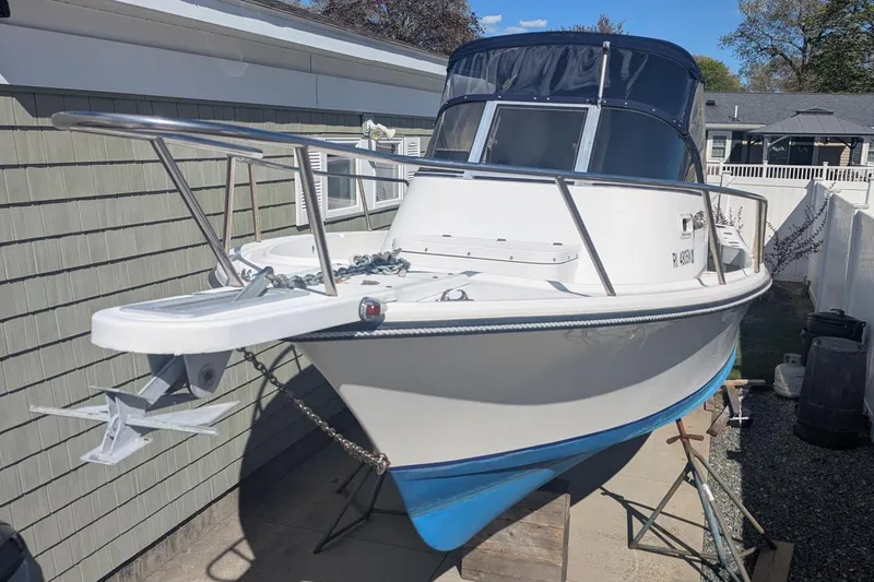 Slide: The Image of 1993 Shamrock 220 Walkaround boat with blue hull, docked outdoors. - 2