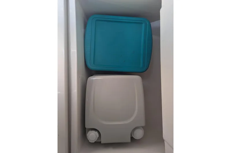 Slide: The Image of Storage compartments on a 1993 Shamrock 220 Walkaround boat, featuring blue and white containers. - 27
