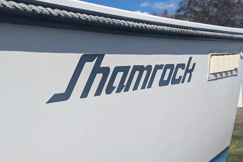 Slide: The Image of 1993 Shamrock 220 Walkaround boat with logo on the side, under a clear sky. - 5