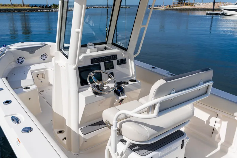 Slide: The Image of 2027 Sailfish 232 CC boat interior with steering wheel and seating, docked by calm waters. - 22