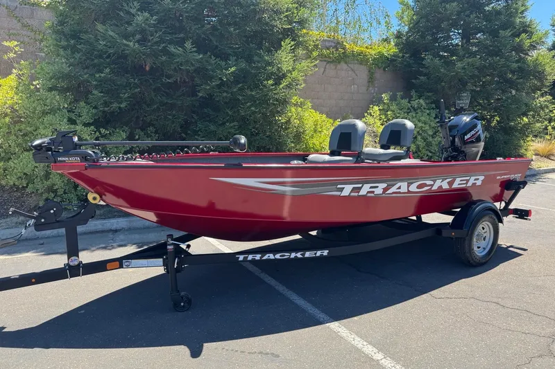 Slide: The Image of 2026 Tracker Super Guide V-16 T fishing boat in vibrant red, parked outdoors. - 2