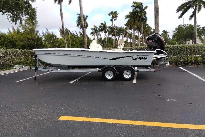 Slide: The Image of 2026 Mako Pro Skiff 19 CC boat on trailer in parking lot with palm trees. - 93