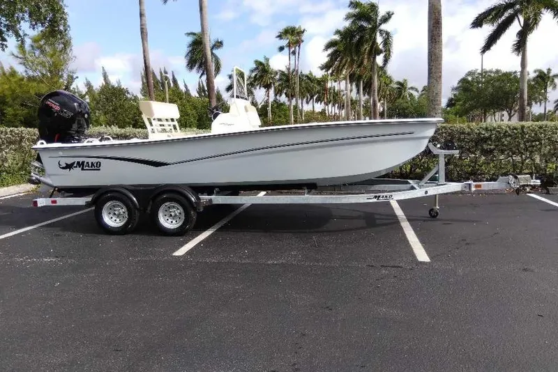Slide: The Image of 2026 Mako Pro Skiff 19 CC boat on trailer in parking lot with palm trees. - 95