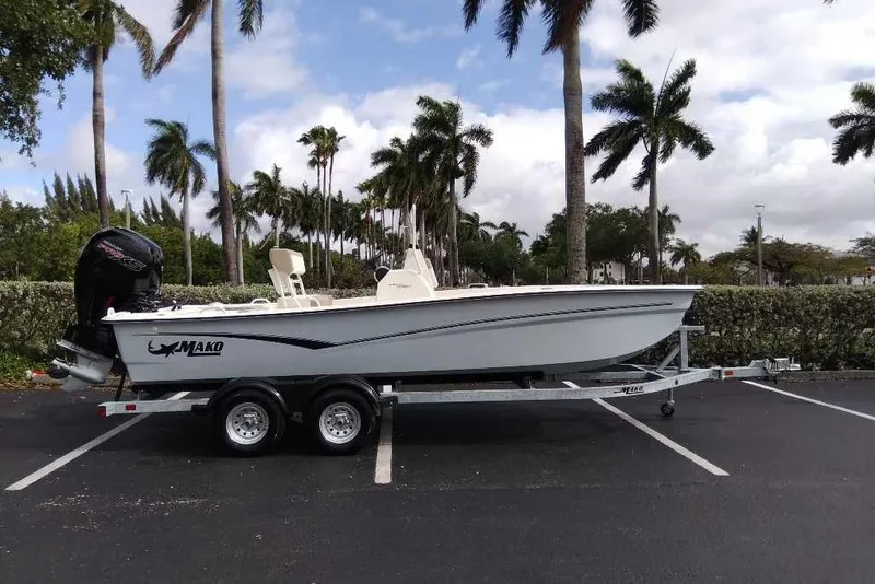 Slide: The Image of 2026 Mako Pro Skiff 19 CC boat on trailer, parked under palm trees. - 96