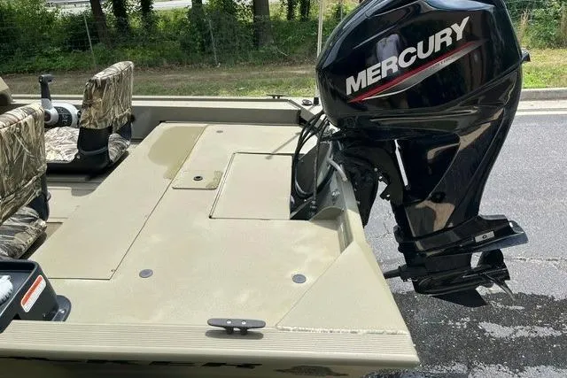 Slide: The Image of 2024 Tracker Grizzly 1648 SC boat with Mercury outboard motor, camo seats, and spacious deck. - 4