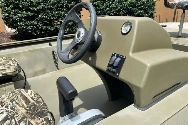 Slide: The Image of 2024 Tracker Grizzly 1648 SC boat interior with steering wheel and camo seats. - 7