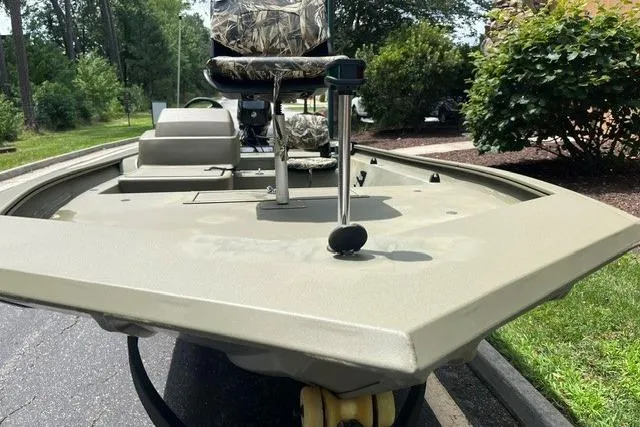 Slide: The Image of 2024 Tracker Grizzly 1648 SC boat, front view, parked outdoors with greenery. - 2