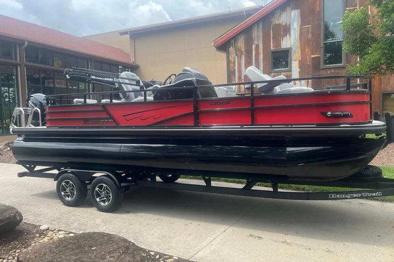 Slide: The Image of 2026 Ranger 220F pontoon boat on trailer, red and black design, parked outdoors. - 1