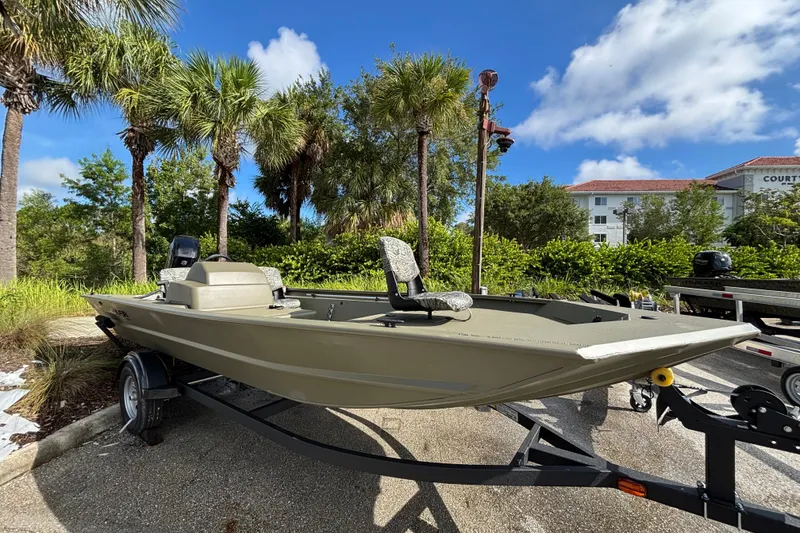 The Image of 2026 Tracker Grizzly 1754 SC boat on trailer, surrounded by palm trees and clear sky. - 0