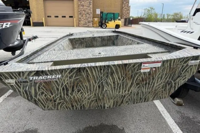 Slide: The Image of 2026 Tracker Grizzly 1648 Utility boat with camouflage design in a parking lot. - 2