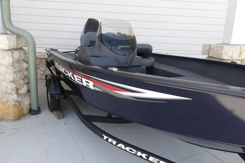Slide: The Image of 2026 Tracker Super Guide V-16 SC boat on trailer, parked near stone wall. - 7