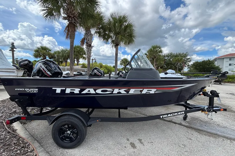 The Image of 2026 Tracker Pro Guide V-16 WT boat on trailer, parked outdoors under palm trees. - 0