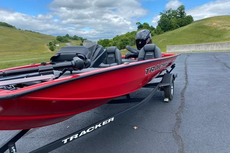 Slide: The Image of Red 2026 Tracker Pro Team 190 boat on trailer, parked on asphalt with grassy hills in background. - 2