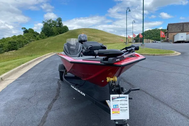 Slide: The Image of 2026 Tracker Pro Team 190 boat on trailer, parked on asphalt near grassy hill. - 3