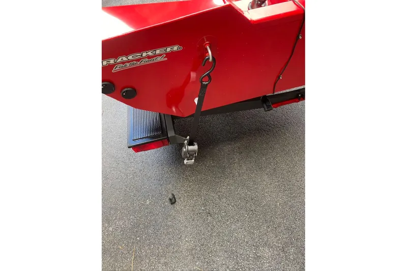 Slide: The Image of Red 2026 Tracker Pro Team 190 boat detail with logo and hitch on asphalt. - 6
