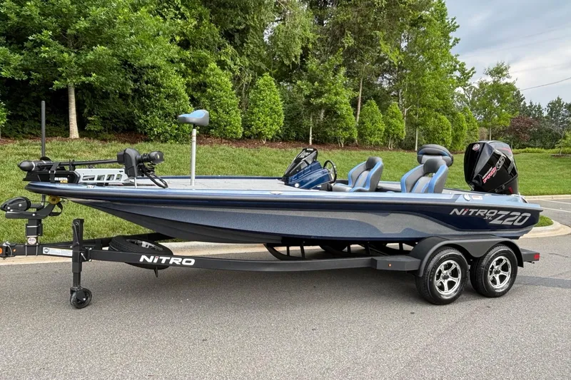 The Image of 2026 Nitro Z20 XL boat on trailer, parked on road with lush greenery background. - 0