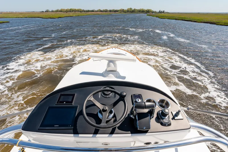 Slide: The Image of Helm view of 2023 Valhalla Boatworks V-46 navigating a scenic waterway. - 23