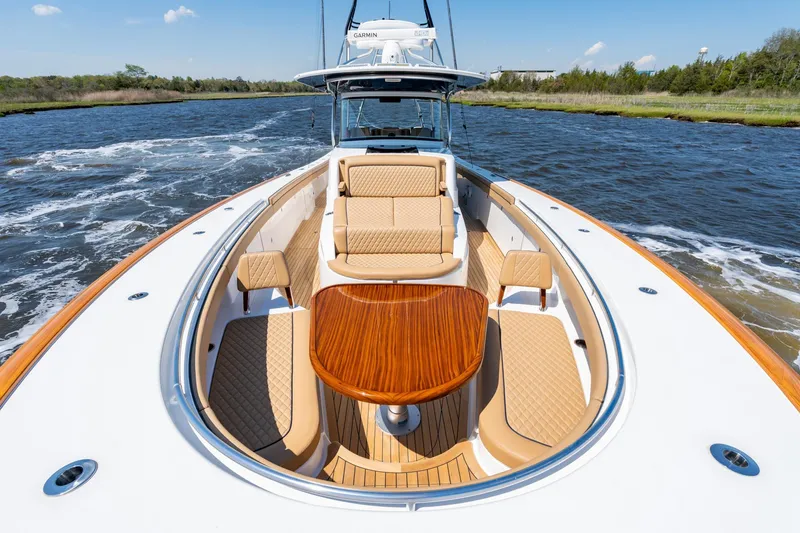 Slide: The Image of 2023 Valhalla Boatworks V-46 luxury boat with elegant seating and wooden table on open water. - 9