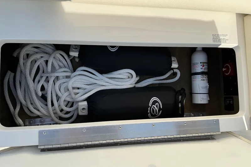 Slide: The Image of Storage compartment in a 2019 Cobalt CS23 boat with ropes, fenders, and a fire extinguisher. - 12