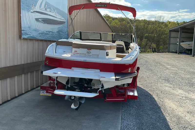 Slide: The Image of 2019 Cobalt CS23 boat with red exterior, parked outdoors near a storage facility. - 3