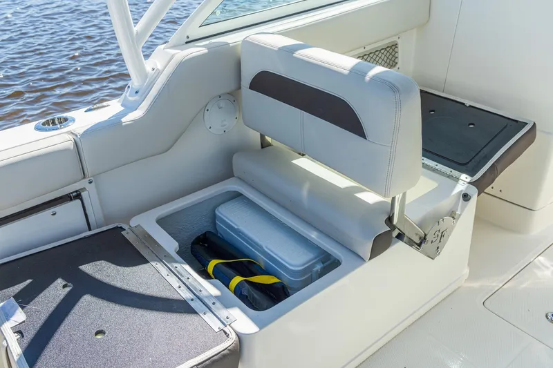 Slide: The Image of 2027 Sailfish 245 DC boat seat with storage compartment open, revealing cooler and gear. - 11