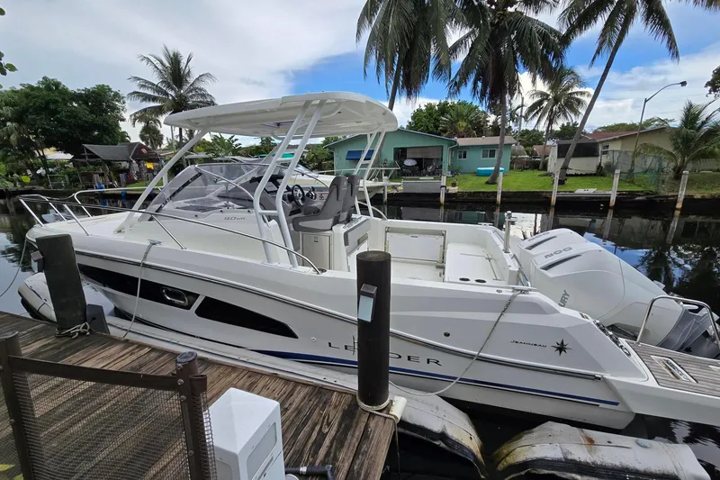 Slide: The Image of 2020 Jeanneau Leader 9.0 WA boat docked by palm trees and waterfront homes. - 2