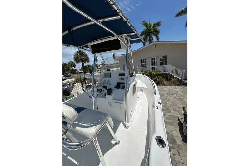 Slide: The Image of 2008 Pro-Line 20 Sport boat with blue canopy, docked near a house with palm trees. - 11