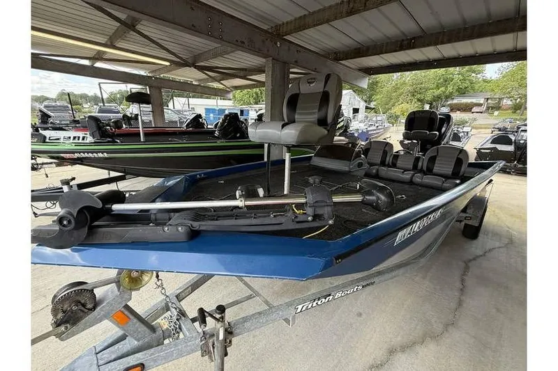 Slide: The Image of 2008 Triton TS-18 fishing boat on trailer under shelter, featuring seating and motor. - 7