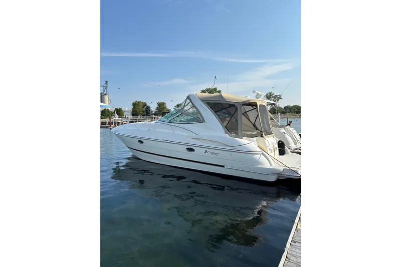 The Image of 2003 Cruisers Yachts 3470 Express docked on calm water under clear blue sky. - 0