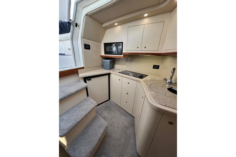 Slide: The Image of Interior of 2003 Cruisers Yachts 3470 Express, featuring a compact kitchen with modern amenities. - 16