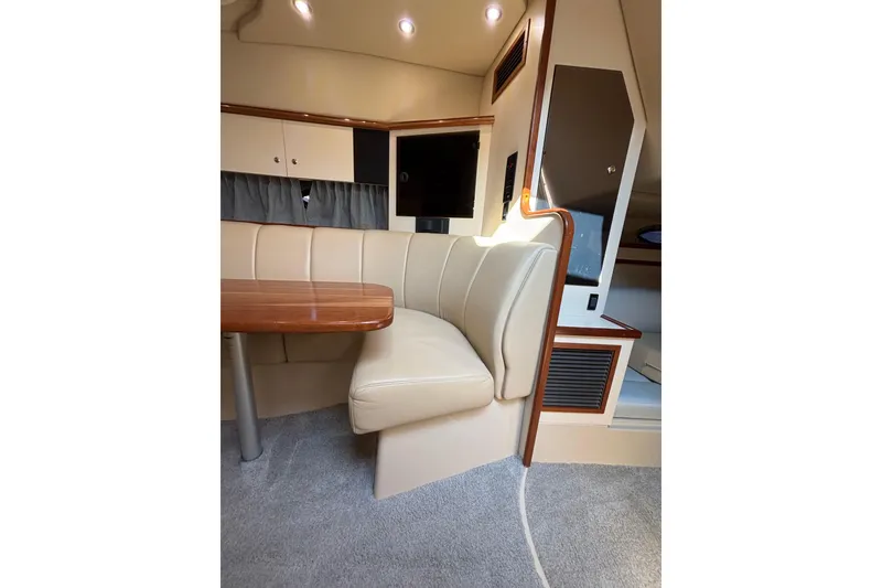 Slide: The Image of Interior of 2003 Cruisers Yachts 3470 Express with beige seating and wooden table. - 19