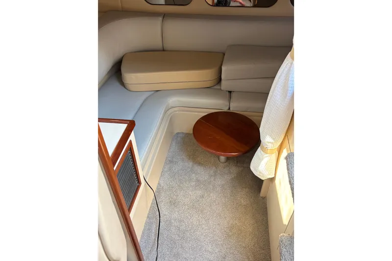 Slide: The Image of Interior of 2003 Cruisers Yachts 3470 Express with beige seating and small wooden table. - 25