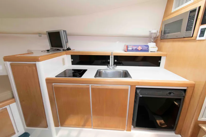 Slide: The Image of 1995 Bertram 30 Moppie yacht interior kitchen with sink, stove, and microwave. - 15