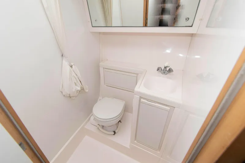 Slide: The Image of Compact bathroom in a 1995 Bertram 30 Moppie boat, featuring a toilet and sink. - 18